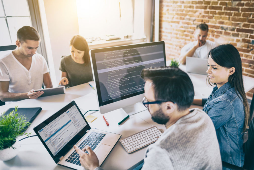 A group of people sit in an office with screens showing the best programming languages to work in tech