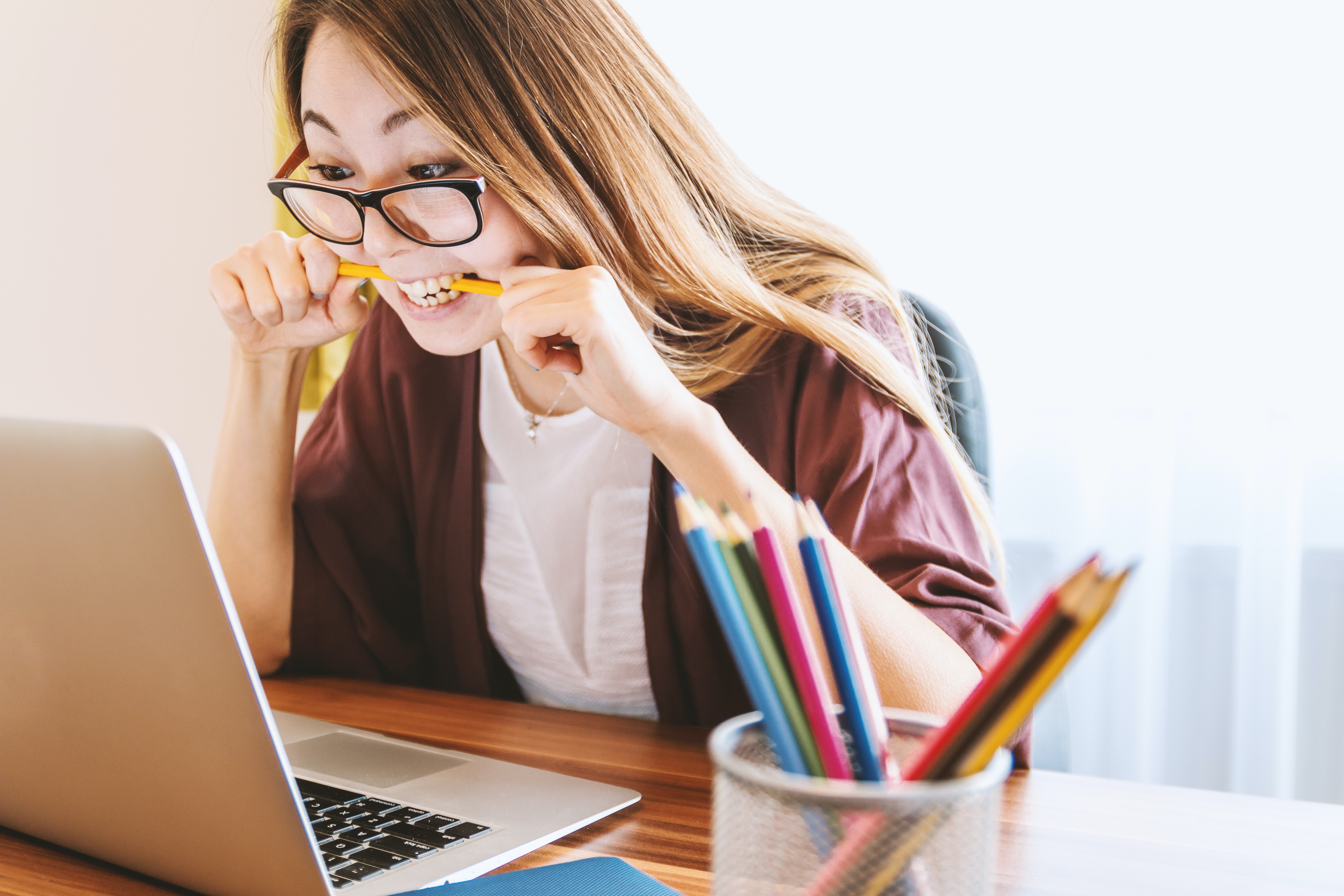 Young female bites down on her pencil in frustration