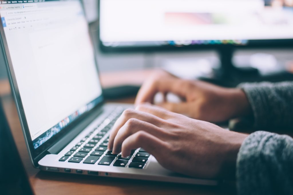 close up of male hands typing on a laptop keyboardping on a laptop