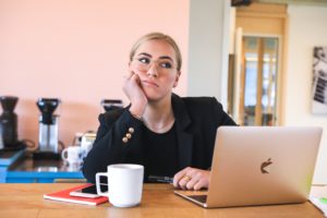 a young attractive professional woman sits in front of her laptop looking bored